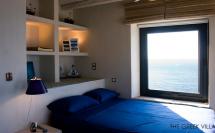 греческие интерьеры - спальня полками в изголовье кровати и синим покрывалом